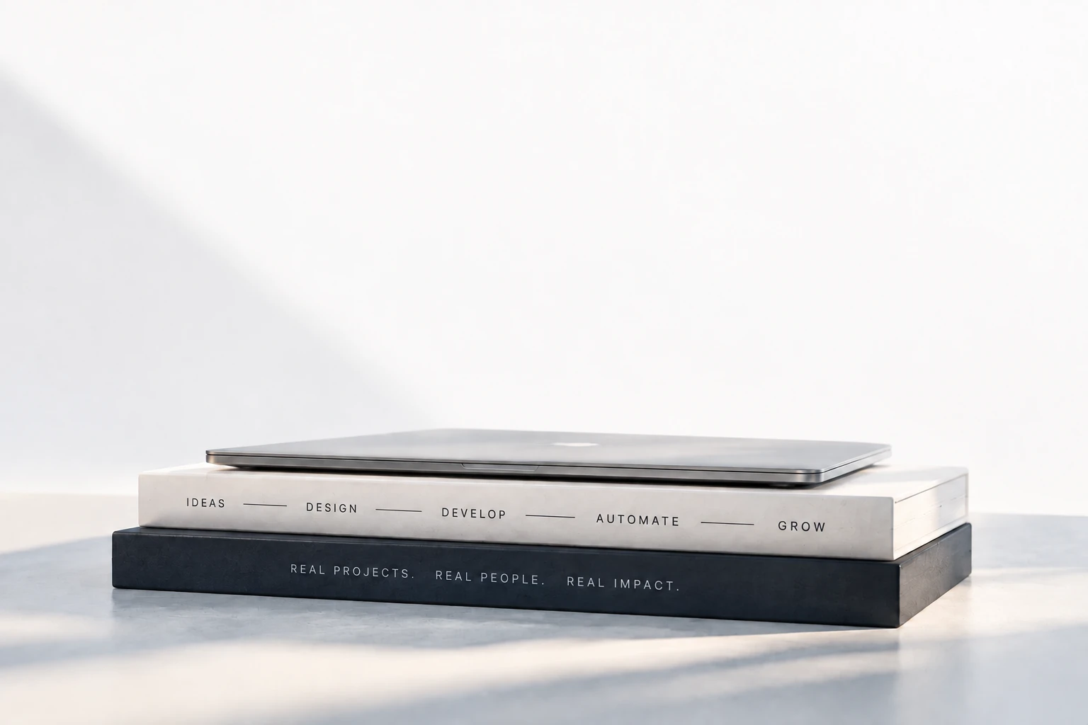 Closed silver laptop on books representing ideas, design, development, automation, and growth